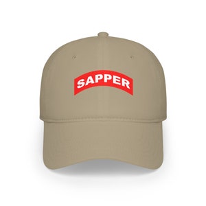 May include: A tan baseball cap with a curved brim. The cap features the word "SAPPER" in white block letters on a red curved banner across the front. The cap is made of a durable fabric.