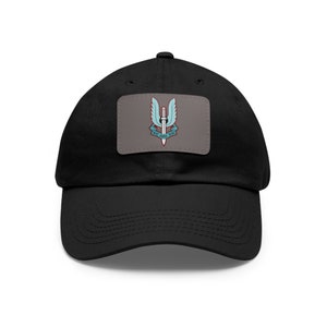 May include: Black baseball cap with a gray patch featuring a winged dagger emblem in light blue and white. The text "WHO DARES WINS" is below the emblem. A classic, adjustable hat.