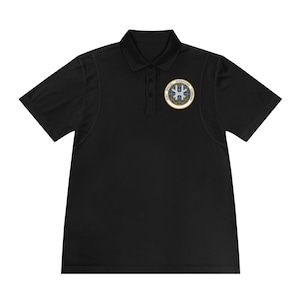 May include: Black polo shirt with a small embroidered patch on the left chest. The patch is a circle with a gold border and a blue and white star inside. The text "Special Operations Command" is written around the star.