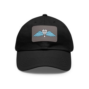 May include: Black baseball cap with a patch featuring a parachute design with light blue wings and a white parachute on a gray background. The cap is made of a durable fabric and has a curved brim.