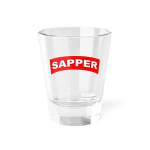 May include: A clear glass shot glass with the word "SAPPER" printed in red on the front.