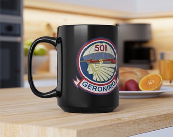 May include: Black ceramic mug featuring a colorful emblem with the number "501" and the word "GERONIMO". The emblem includes a Native American profile, lightning bolts, and a parachute design. The mug has a large handle.