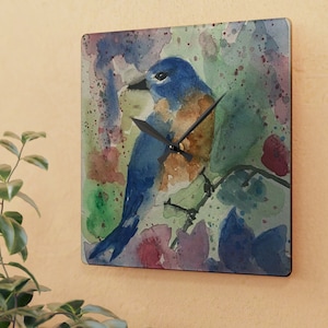 May include: A watercolor painting of a bluebird perched on a branch with a colorful background. The bird is facing to the right and has a brown breast. The background is a mix of green, blue, purple, and pink.