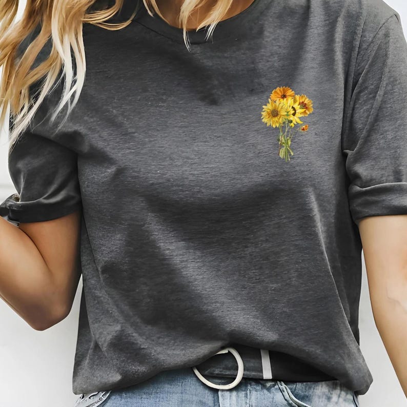 May include: A grey t-shirt with a small bouquet of yellow sunflowers printed on the left side of the chest.