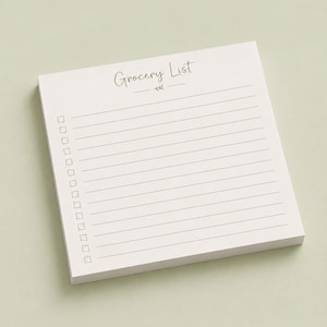 May include: A square notepad with white paper featuring the text Grocery List at the top, followed by a small decorative leaf icon, and a series of horizontal lines with empty square checkboxes along the left side for organizing tasks.