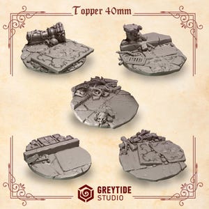 May include: Five gray, detailed miniature bases, each with a unique design. The bases are round and feature elements like broken stone, skulls, and architectural details. The text "Topper 40mm" is at the top.