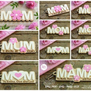 May include: Wooden keychains with the words "MOM" and "MUM" in a playful font, adorned with pink flower accents. Some keychains include names. The keychains are displayed on a wooden surface with pink flowers and fabric.