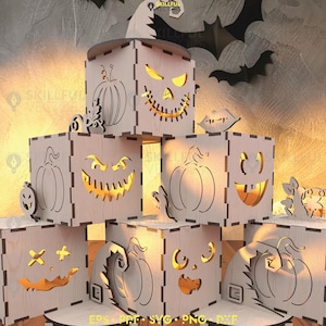 Könnte beinhalten: Eine Ansammlung von Holzlaternen zum Thema Halloween. Jede würfelförmige Laterne weist geschnitzte Kürbis- und gruselige Gesichtsdesigns auf. Die Laternen werden von innen beleuchtet und erzeugen ein warmes Leuchten. Ein Hexenhut und Fledermäuse sind ebenfalls zu sehen.