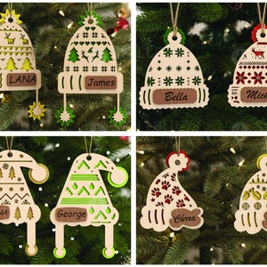 Puede incluir: Adornos navideños de madera con forma de gorros, cada uno con una etiqueta con nombre. Los adornos presentan cortes decorativos y están adornados con diseños festivos, incluyendo estrellas, árboles y copos de nieve. Los nombres incluyen Lana, James, Bella, Michael, Polina, George, Chrra y Anna.