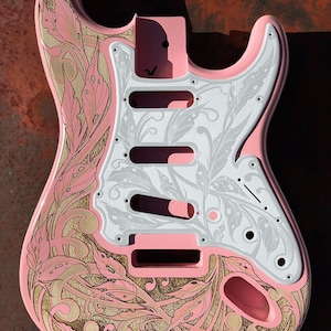 May include: A pink electric guitar body with a white and gold floral design. The guitar body is engraved with a floral pattern and the text "DUSTSTORM ENGRAVING".