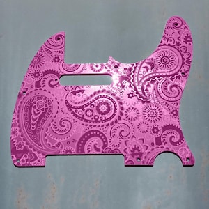 Op de afbeelding: Een roze paisley-gepatroneerde gitaar pickguard. De pickguard is gemaakt van metaal en heeft een glanzende afwerking.