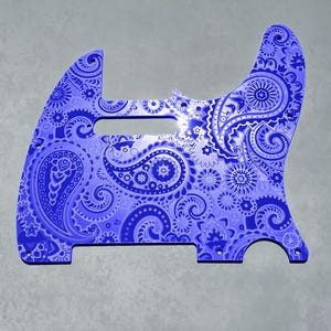 Op de afbeelding: Een blauwe en witte paisley-gepatroneerde gitaar pickguard. De pickguard is gemaakt van een duurzaam materiaal en is ontworpen om te passen op een Fender Stratocaster gitaar.
