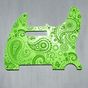 Op de afbeelding: Een felgroene gitaar pickguard met een gedetailleerd paisley patroon. De pickguard is ontworpen voor een Telecaster-stijl gitaar en heeft een glanzende afwerking. De tekst "DUST STORM ENGRAVING" staat onderaan.
