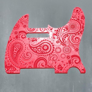 Op de afbeelding: Een rode gitaar slagplaat met paisley patroon. De slagplaat heeft een complex ontwerp van wervelende paisley elementen en bloemmotieven. De slagplaat is felrood van kleur en heeft een glanzende afwerking. De tekst "DUST STORM ENGRAVING" staat onderaan.