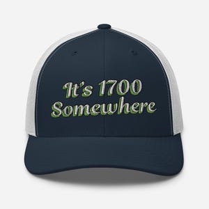 Może przedstawiać: Czapka trucker w kolorze granatowym i białym z haftem "It's 1700 Somewhere" w kolorze zielonym.