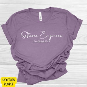 May include: A heather purple t-shirt with the text "Software Engineer Est. 08.08.2019" in white.