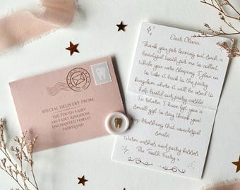 May include: A pink envelope with a tooth-shaped stamp and a wax seal, alongside a handwritten note. The envelope reads "Special Delivery From: The Tooth Fairy." The note is addressed to "Olivia" and signed "The Tooth Fairy."