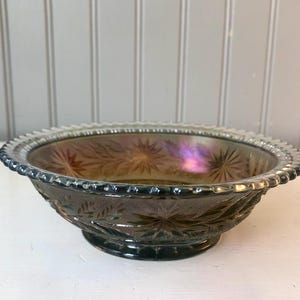 May include: A vintage iridescent glass bowl with a scalloped edge and a starburst pattern. The bowl is a deep green color with hints of purple and brown.