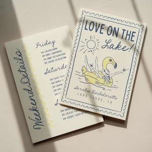 May include: Two cream-colored cards with navy and yellow accents. One card reads "Weekend Details" and lists a schedule. The other card says "Love on the Lake!" with a flamingo illustration and "Sarah's Bachelorette, Lake Tahoe, CA."