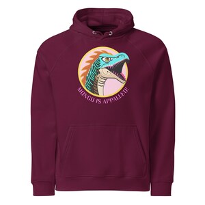 May include: Burgundy hoodie with a graphic of a blue and green dinosaur with a pink and yellow background. The text "MONGO IS APPALLED!" is printed in pink below the dinosaur.