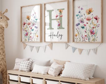 May include: Three framed prints with watercolor floral designs and the letter H with the name Hailey. The prints are hung on a white wall above a wooden bench with pillows.