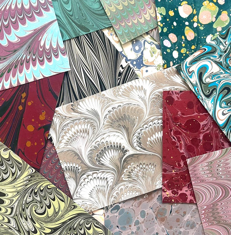 May include: Assortment of marbled papers in various colors and patterns, including red, green, blue, and white. The papers have a unique, swirling design.