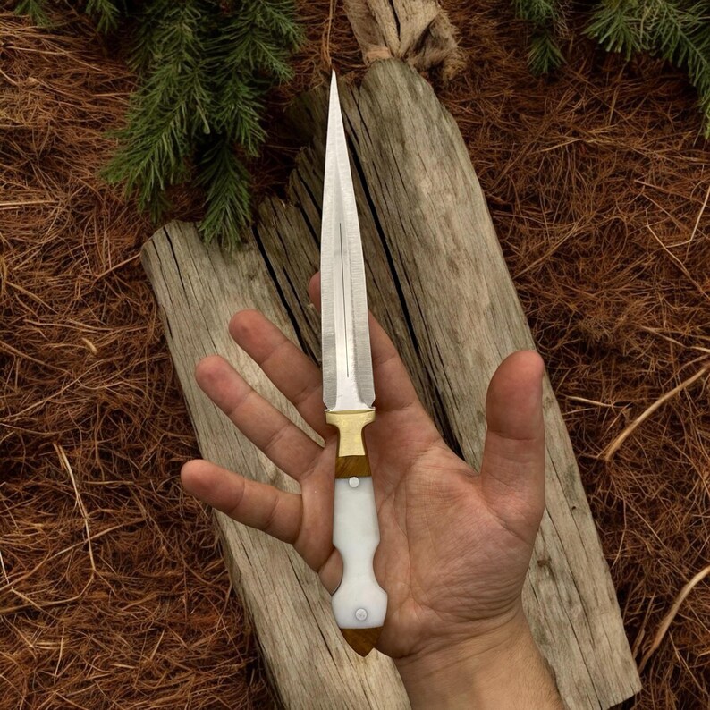 May include: A silver dagger with a white and brown handle. The dagger has a sharp point and a double-edged blade.