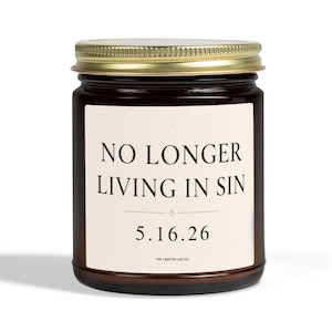 Könnte beinhalten: Eine braune Glas-Kerze mit goldenem Deckel. Auf dem Etikett steht "NO LONGER LIVING IN SIN" über dem Datum "5.16.26". Die Kerze steht vor einem weißen Hintergrund.