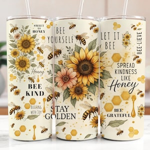May include: Three stainless steel tumblers with a white background and bee-themed designs. The tumblers feature illustrations of sunflowers, bees, and honeycomb. The text on the tumblers includes phrases like "Bee Yourself", "Let It Bee", and "Spread Kindness Like Honey".