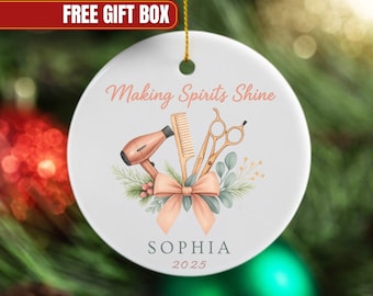 May include: White ceramic ornament with a gold string, featuring a salon theme. It has a hair dryer, comb, scissors, and a bow. The text "Making Spirits Shine", the name "SOPHIA", and the year "2025" are also displayed.
