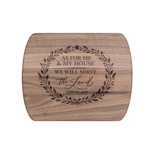 May include: Wooden chopping board with rounded edges. The board has the engraved text "AS FOR ME & MY HOUSE WE WILL SERVE the Lord" surrounded by a floral wreath. The text "JOSHUA 24:15" is below the main text.