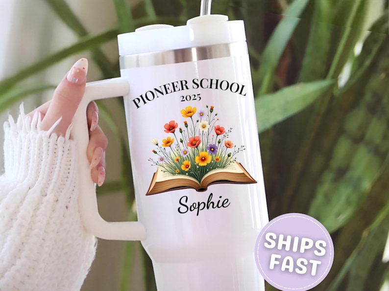 May include: White insulated tumbler with a handle, featuring the text "PIONEER SCHOOL 2025" and a floral design above the name "Sophie". The tumbler has a white lid and a straw.