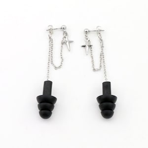May include: A pair of silver-toned earrings featuring a stud post connected to a dangling silver chain and a small four-pointed star charm. The chain attaches to a black, tiered, conical-shaped earplug-style component at the base of each earring.