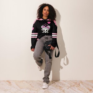 Girl wearing the Lil Miss Mosh Pit cute pink and black jersey with skull and pink bow ties. Hockey long sleeve rave jersey for girls and edm lovers. Made of Recycled materials and made to order for sustainability!
