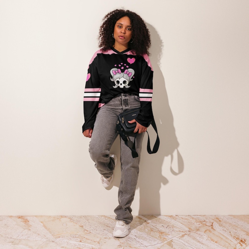 Girl wearing the Lil Miss Mosh Pit cute pink and black jersey with skull and pink bow ties. Hockey long sleeve rave jersey for girls and edm lovers. Made of Recycled materials and made to order for sustainability!