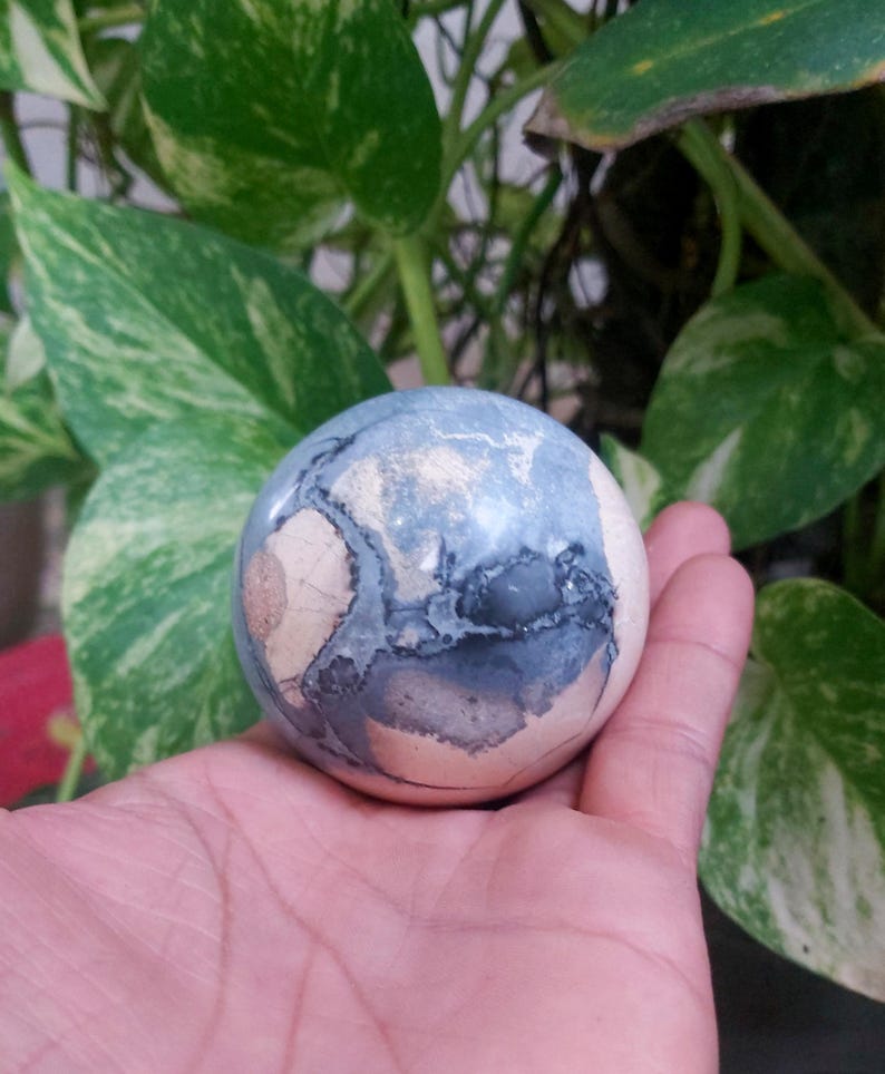 May include: A smooth, round, blue and white agate sphere with swirling patterns. The sphere is about the size of a golf ball.