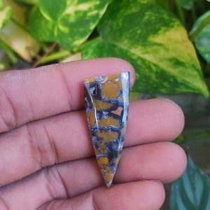May include: A yellow and blue agate cabochon with a pointed shape. The stone has a unique pattern of swirls and veins.