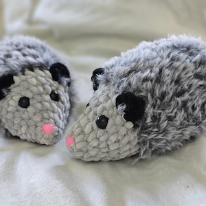 May include: Two gray and black plush opossum toys with pink noses. The opossums are made of soft, fuzzy fabric and have black eyes.
