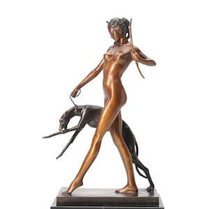 May include: A bronze sculpture of a standing figure holding a bow and a leash attached to a dark-toned greyhound. The figure is depicted in a walking pose, mounted on a rectangular black marble base with a smooth, polished metallic finish.