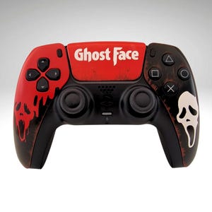 May include: A black and red PlayStation 5 controller featuring a Ghost Face design. The controller has a red faceplate with the words "Ghost Face" printed in white. The back of the controller has a black and white design with a Ghost Face mask.