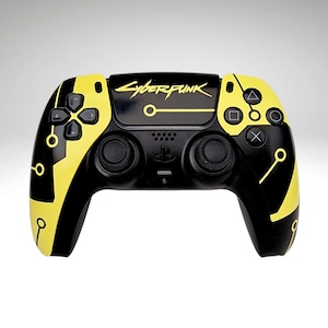 May include: A black and yellow Cyberpunk-themed PlayStation 5 controller. The controller features the game's logo and design elements in yellow against a black background. The controller has the standard button layout.