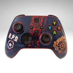 May include: A blue and red Xbox controller with a blood splatter design. The controller has the words "R.P.D." and a star on the left side and the words "R.P.D." and a Raccoon City Police Department logo on the right side.
