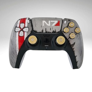 Peut inclure: Une manette PlayStation 5 DualSense personnalisée avec un design gris et noir vieilli. La manette présente une bande rouge et blanche sur le côté gauche et le logo "NZ" en haut. La manette a des boutons dorés en forme de balle.