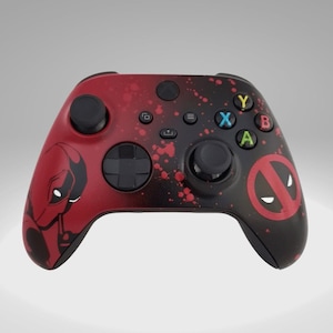 May include: A custom Xbox controller with a red and black Deadpool design. The controller features a red splatter effect, a Deadpool character illustration, and the Deadpool logo. The buttons are multi-coloured.