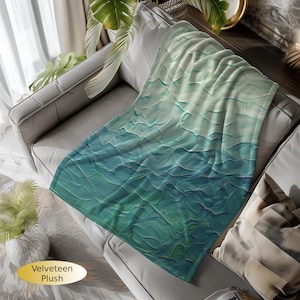 May include: A soft, plush throw blanket with a blue and green abstract pattern. The blanket is made of a velvety material and is perfect for adding a touch of color and comfort to any room.
