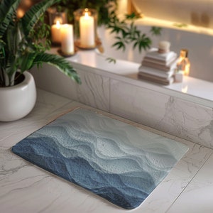 May include: A blue and white bath mat with a wavy pattern. The mat is made of a soft, absorbent material and is perfect for adding a touch of style to your bathroom.