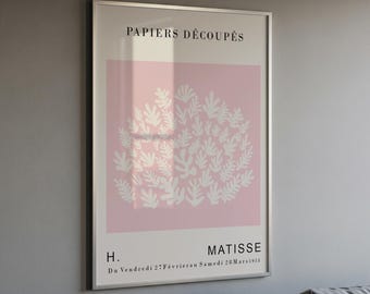 Op de afbeelding: Een ingelijste kunstdruk met de tekst PAPIERS DÉCOUPÉS bovenaan en H. MATISSE onderaan. In het midden staat een lichtroze vierkant met een cluster van witte, organische, bladachtige vormen. De onderste tekst luidt Du Vendredi 27 Février au Samedi 28 Mars 1953.