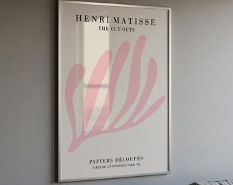 Op de afbeelding: Een ingelijste kunstprint met de tekst HENRI MATISSE THE CUT-OUTS bovenaan en PAPIERS DÉCOUPÉS 70. RUE DE L'UNIVERSITÉ. PARIS VII onderaan. Het midden toont een grote, abstracte, lichtroze organische vorm op een witte achtergrond.