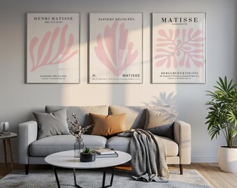 May include: Three framed wall art prints featuring Henri Matisse's pink abstract organic shapes on a cream background. The prints include text such as Henri Matisse The Cut-Outs, Papiers Découpés, and Matisse, displayed in a horizontal row above a sofa.