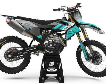 May include: A black and turquoise motocross bike with the number 84 on the side. The bike is on a black stand and has Dunlop tires.